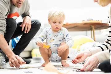 Image showing Parents playing games with child. Little toddler doing puzzle. Infant baby boy learns to solve problems and develops cognitive skills. Child development concept