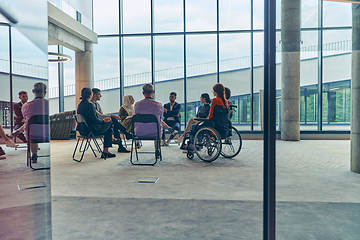 Image showing A diverse group of young business entrepreneurs gathered in a circle for a meeting, discussing corporate challenges and innovative solutions within the modern confines of a large corporation