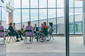 Image showing A diverse group of young business entrepreneurs gathered in a circle for a meeting, discussing corporate challenges and innovative solutions within the modern confines of a large corporation