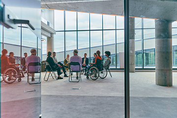 Image showing A diverse group of young business entrepreneurs gathered in a circle for a meeting, discussing corporate challenges and innovative solutions within the modern confines of a large corporation