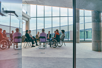 Image showing A diverse group of young business entrepreneurs gathered in a circle for a meeting, discussing corporate challenges and innovative solutions within the modern confines of a large corporation