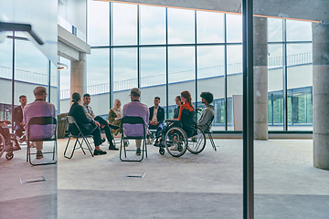 Image showing A diverse group of young business entrepreneurs gathered in a circle for a meeting, discussing corporate challenges and innovative solutions within the modern confines of a large corporation