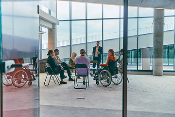 Image showing A diverse group of young business entrepreneurs gathered in a circle for a meeting, discussing corporate challenges and innovative solutions within the modern confines of a large corporation