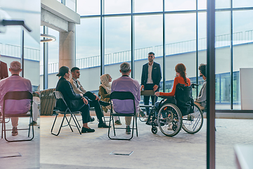 Image showing A diverse group of young business entrepreneurs gathered in a circle for a meeting, discussing corporate challenges and innovative solutions within the modern confines of a large corporation