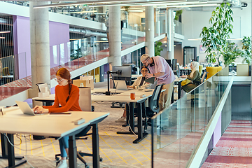 Image showing In a modern startup office, a professional businesswoman with orange hair sitting at her laptop, epitomizing innovation and productivity in her contemporary workspace.