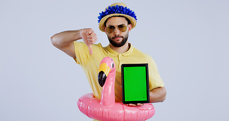 Image showing Green screen, tablet and man with thumbs down in studio for travel agency, review or service feedback on grey background. Digital, space and sad male traveler with emoji vote for app disappointment