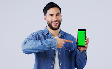 Image showing Man, smartphone or pointing to green screen in portrait, mockup space or happy for advertising. Arab person, smile or face in marketing of tracking markers, mobile app or contact by white background