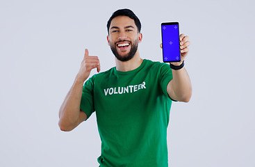 Image showing Green screen, phone and thumbs up by volunteer man portrait in studio with news on grey background. Smartphone, space and face of male activist with thank you emoji for charity, donation or support