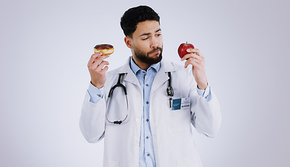 Image showing Healthy, diet and doctor with choice of food, apple or donut in hands for nutrition in studio white background. Nutritionist, thinking and man with a decision for health with fruit and dessert