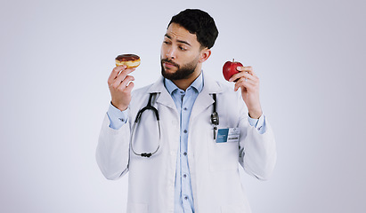 Image showing Doctor, apple or donut for choice in health for nutrition in studio on white background for mock up. Man, male model or medical professional with thinking of diet, food or offer for eating in Mexico