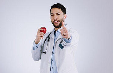 Image showing Happy man, doctor and apple with thumbs up for diet, good health or approval against a gray studio background. Portrait of male person or medical nurse with red organic fruit, like emoji or yes sign