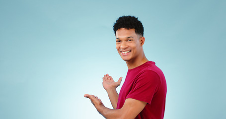 Image showing Portrait, happy man and smile with presentation in studio for promotion mockup on blue background. New York, male model and hand for show of announcement, offer and discount in space with gesture