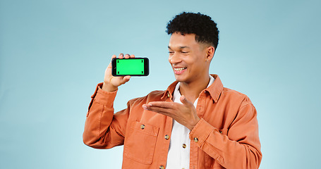 Image showing Happy man, show and phone with greenscreen in studio for social media mock up on blue background. Male model, hand and mobile app in presentation or announcement online, deal or promotion by internet