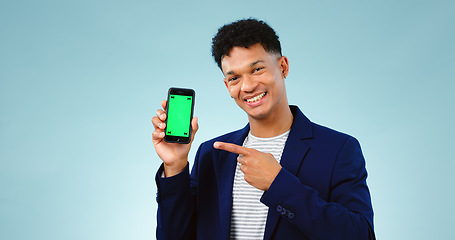 Image showing Happy man, pointing and phone for green screen on blue background in studio, portrait and mockup in New York. Male model, entrepreneur or creative with mobile of offer, promotion or discount on web