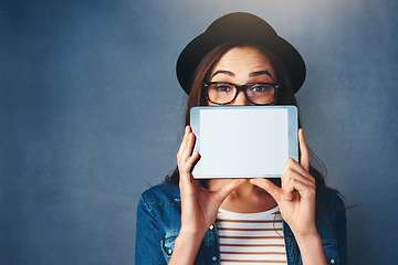 Image showing Portrait, tablet screen and space with a fashion woman in studio on a blue background for social media marketing. Face, display and style with a young person holding technology for advertising mockup