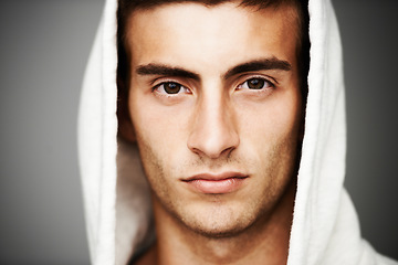 Image showing Confident, portrait and man in hoodie for fashion isolated on a gray background. Serious young person, face of model and streetwear clothes, casual and cool facial expression in Spain on a backdrop