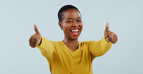 Image showing Happy black woman, portrait and thumbs up in winning or good job against a gray studio background. African female person smile with like emoji, yes sign or OK in thank you for approval or success