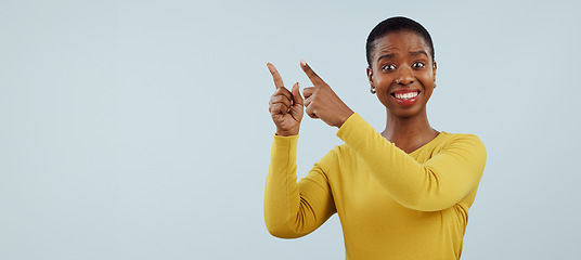 Image showing Happy black woman, portrait and pointing up for surprise, advertising or marketing against a gray studio background. African female person smile in wow for deal promotion, sale or discount on mockup