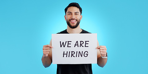 Image showing Portrait, smile and man with we are hiring, poster or announcement in studio on blue background. Recruitment, banner and face of male model with news, announcement or business, opportunity or offer