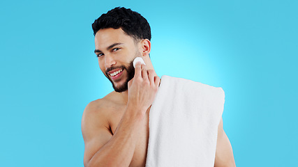 Image showing Skincare, portrait and happy man with cotton pad in studio for luxury, grooming or wellness on blue background. Face, smile and model with facial swab for cleaning, cosmetics or after shower beauty