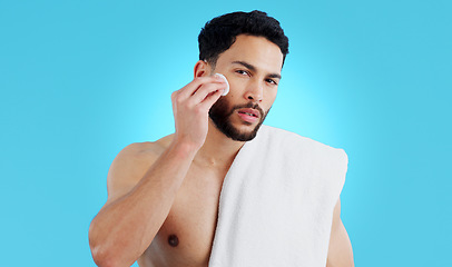 Image showing Skincare, portrait and man with cotton pad in studio for luxury, grooming or wellness on blue background. Face, hands and male model with facial swab for cleaning, cosmetics or after shower beauty