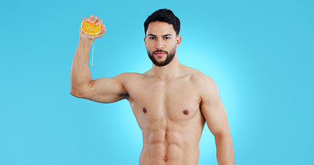 Image showing Orange, splash and portrait of man in studio for vitamin C, natural cosmetics or healthy diet on blue background. Fruit, squeeze or model face with citrus, juice or skin detox, wellness or nutrition