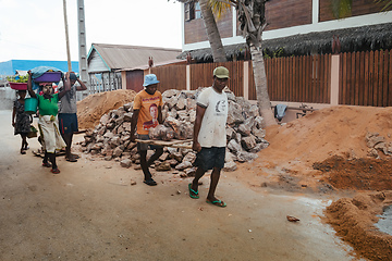 Image showing Malagasy men working hard, manually carrying construction stones. Morondava, Madagascar