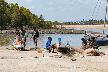 Image showing Fisherman and woman repairing fishing nets at the estuaries of a river. The woman has a traditionally Malagasy painted face