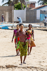 Image showing Malagasy woman with her face painted against the sun and a child in her arms walks along the port in Morondava.