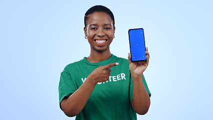 Image showing Woman, volunteering and point at phone with green screen in portrait for mockup on blue background in studio. Black person, happy or smile for internet, cellular or network for homepage on mobile app