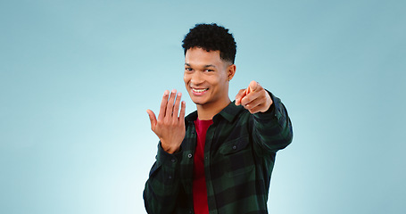 Image showing Man, pointing and invitation for welcome in studio, offer and choice on blue background. Model, happy face and hand gesture for sign up in promotion, deal opportunity and advertising for mockup space