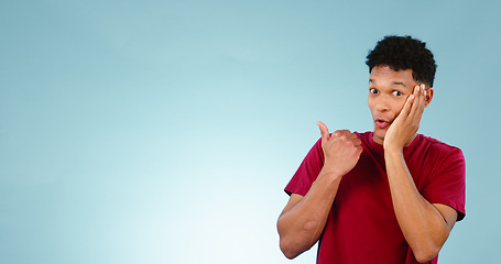 Image showing Excited, man and pointing to announcement in studio with gossip, news or portrait in blue background with information. Confidential, secret and promotion of drama, story or emoji for surprise