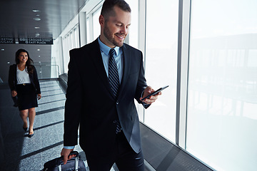 Image showing Business man, cellphone or travel by airport window for reading, thinking or contact in corridor with smile. Entrepreneur, luggage and smartphone with flight schedule for global immigration in London