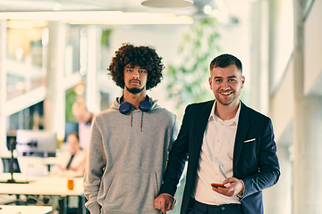 Image showing In a modern startup office setting, a business director and a young African American entrepreneur sit surrounded by their colleagues, embodying diversity and teamwork in the corporate world.