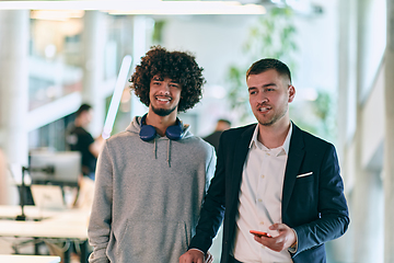 Image showing In a modern startup office setting, a business director and a young African American entrepreneur sit surrounded by their colleagues, embodying diversity and teamwork in the corporate world.