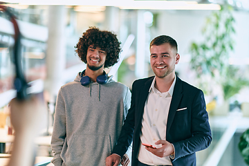 Image showing In a modern startup office setting, a business director and a young African American entrepreneur sit surrounded by their colleagues, embodying diversity and teamwork in the corporate world.