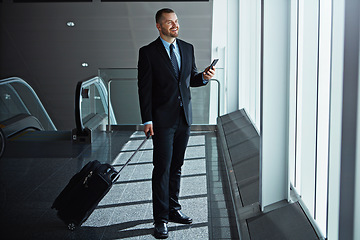 Image showing Happy, thinking or business man in airport with phone, luggage or suitcase waiting to travel. Smile, male entrepreneur or corporate worker texting on social media mobile app on international flight