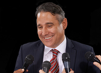 Image showing Man, speech and politician at press conference to media for election, forum or broadcast to audience in studio on black background. Politics, government and happy public speaker talking at microphone