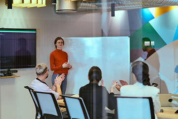 Image showing A pregnant business woman with orange hair confidently presents her business plan to colleagues in a modern glass office, embodying entrepreneurship and innovation