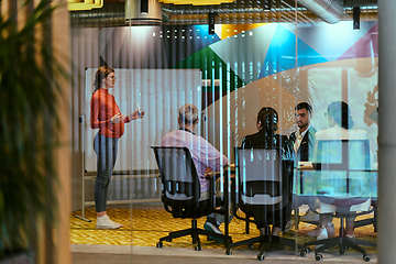 Image showing A pregnant business woman with orange hair confidently presents her business plan to colleagues in a modern glass office, embodying entrepreneurship and innovation