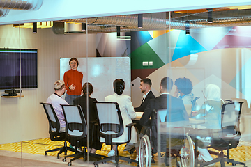 Image showing A pregnant business woman with orange hair confidently presents her business plan to colleagues in a modern glass office, embodying entrepreneurship and innovation