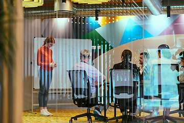 Image showing A pregnant business woman with orange hair confidently presents her business plan to colleagues in a modern glass office, embodying entrepreneurship and innovation