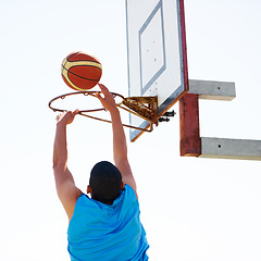 Image showing Man, basketball and dunk jump outdoor for shooting point as athlete, game challenge or fun. Male person, hand and score at hoop for summer exercise match or fitness training sport, player on court