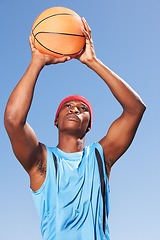 Image showing Man, basketball and player for point in blue sky for fitness challenge or sports train game, match as athlete. Black person, dunk in summer win or goal shoot score in competition, confident on court