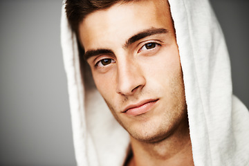 Image showing Serious, portrait and man in hoodie for fashion isolated on a gray background. Confident young person, face of model and streetwear clothes, casual and cool facial expression in Spain on a backdrop
