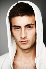 Image showing Serious, portrait and man in hoodie for fashion isolated on a gray background. Confident young person, face of model and streetwear clothes, casual and cool facial expression in Spain on a backdrop