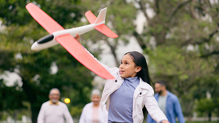 Image showing Outdoor, family and girl with an airplane, playing and child in park with parents for holiday, adventure and weekend outdoors with joy. Happy, group or kid with plane, mom or dad in nature with a toy