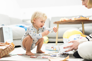 Image showing Parents playing games with child. Little toddler doing puzzle. Infant baby boy learns to solve problems and develops cognitive skills. Child development concept