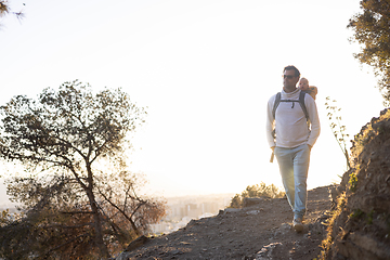 Image showing Young father carrying his infant baby boy son in backpack while tracking around Malaga, Spain in sunset. Family travel and vacation concept