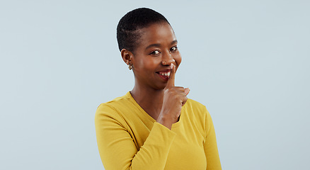 Image showing Secret, portrait and happy black woman with finger on lips in studio for privacy, news or announcement on grey background. Gossip, whisper or model face with confidential hand, emoji or quiet gesture